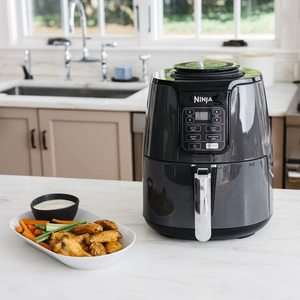 Ninja AF100UK Air Fryer next to fried food.